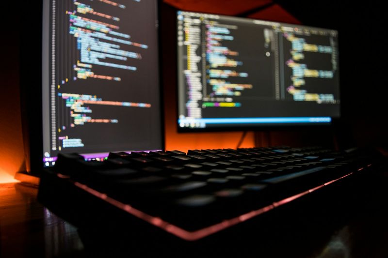 Dual-monitor development setup running code editors, representative of a modern support-and-infrastructure workflow
